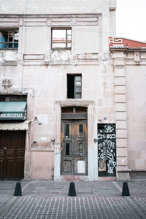 Free Weathered building facade with graffiti and vintage doorway on city street, capturing urban decay. Stock Photo