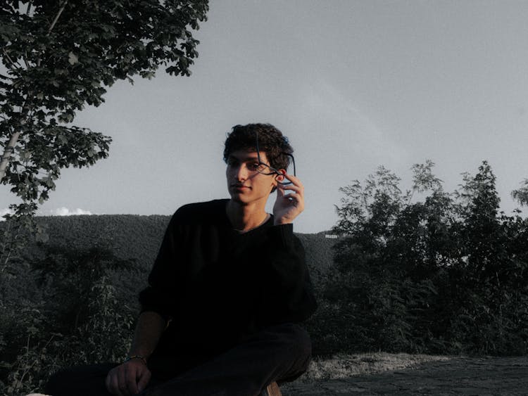 Young Man In Black Sweater Sitting With Eyeglasses In His Hand