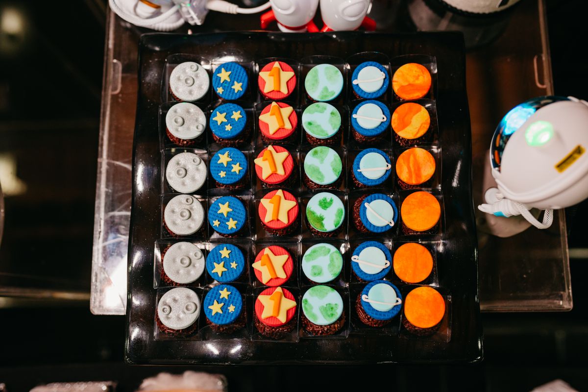 A vibrant collection of space-themed cupcakes featuring planets, moons, and stars. Stock Photo.