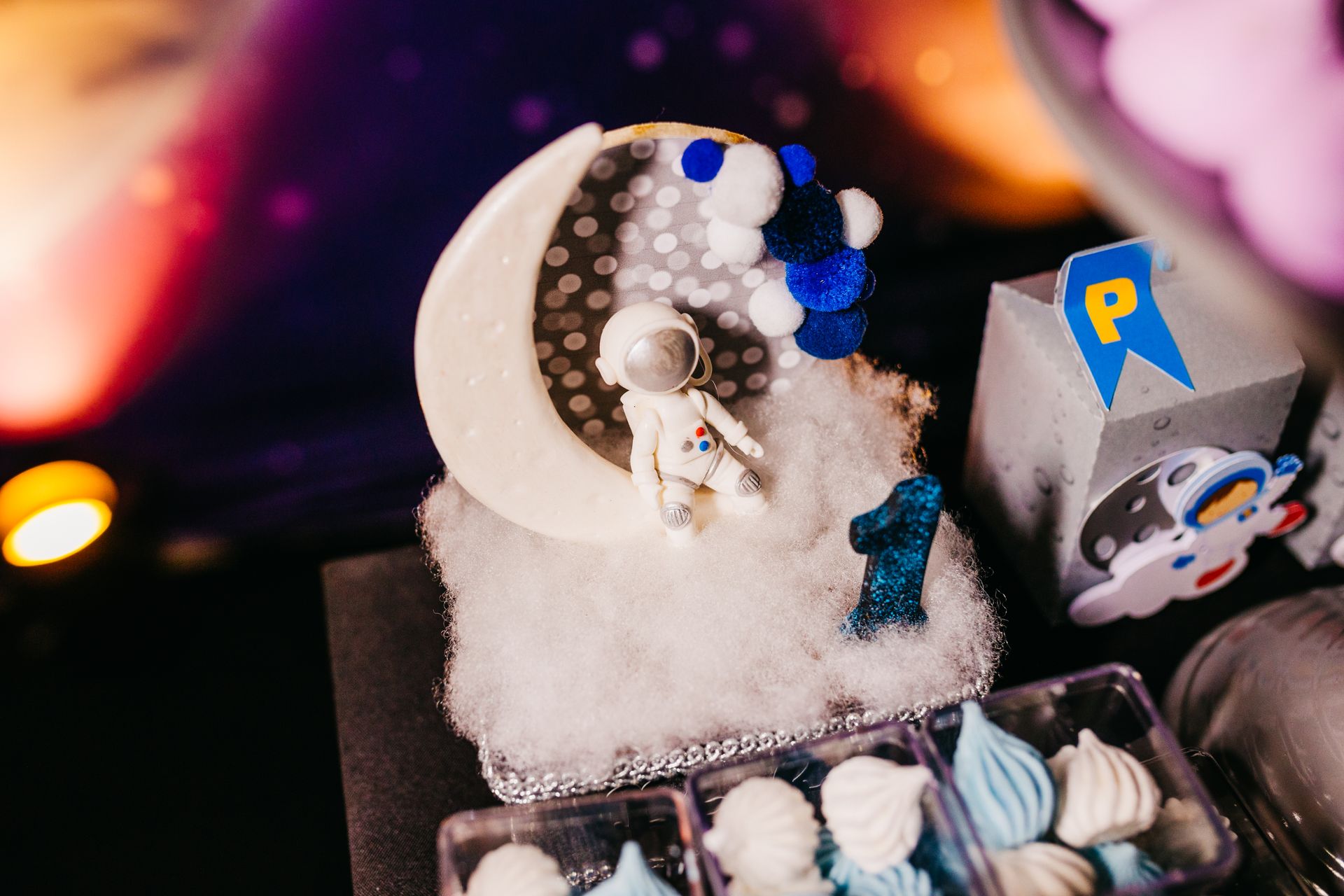 A close-up of a space-themed cake decoration with an astronaut figurine and the number one in a cosmic setting.