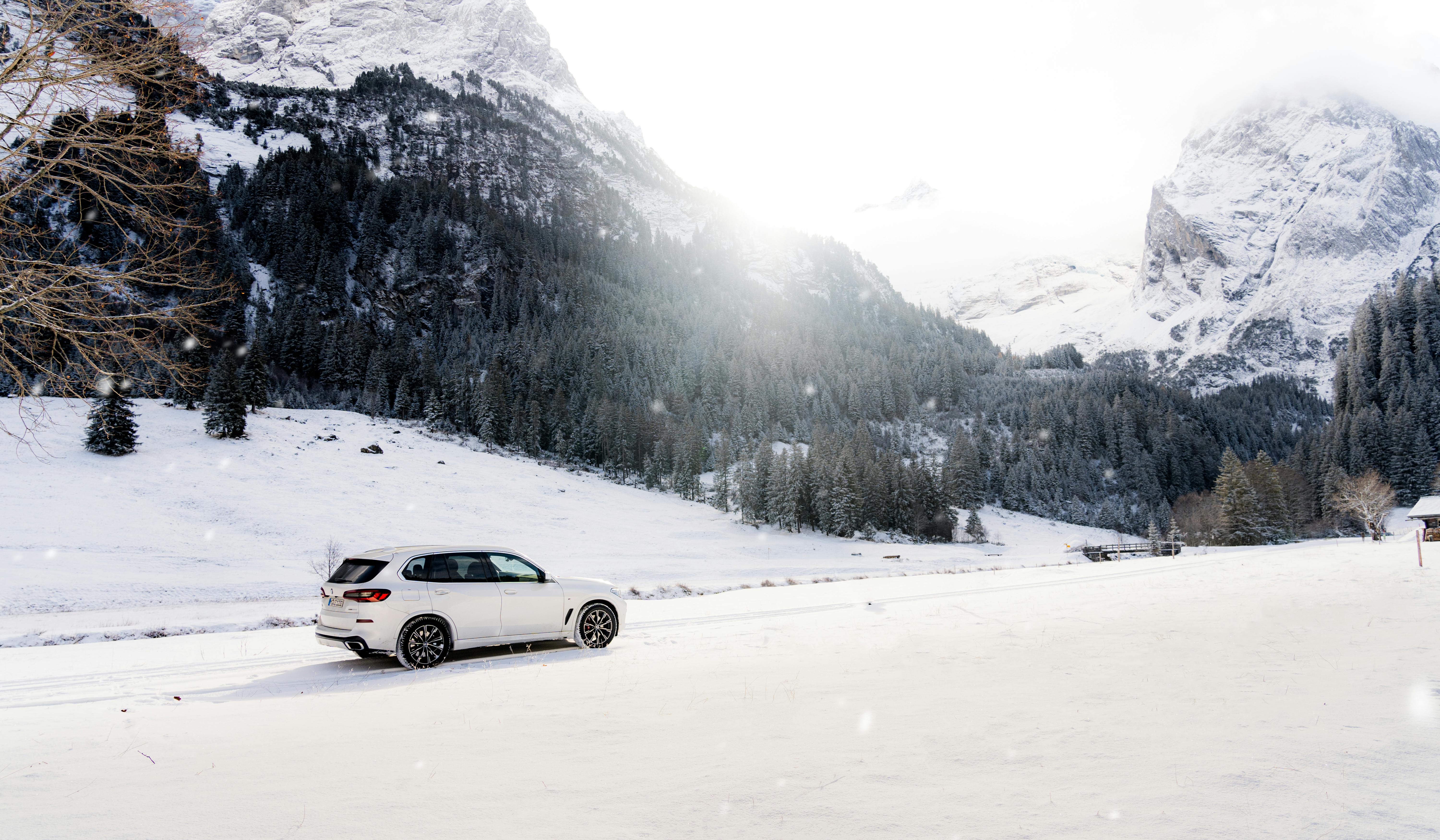 A luxury SUV parked amidst the stunning winter landscape of the Swiss Alps.