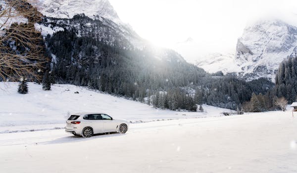 A luxury SUV parked amidst the stunning winter landscape of the Swiss Alps.