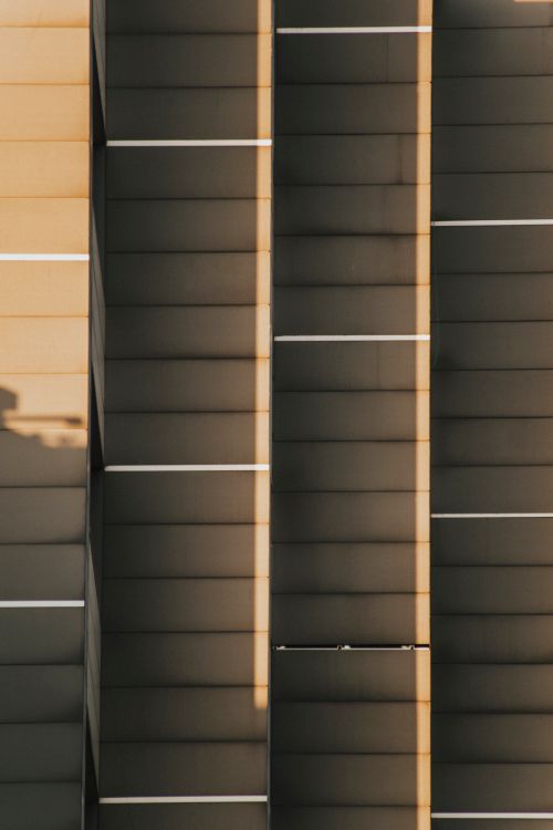Free Vertical shot of a building facade featuring geometric patterns and shadows. Perfect for urban design concepts. Stock Photo