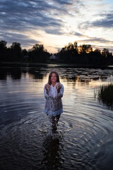 A woman splashing water in a serene lake during a peaceful summer evening.
