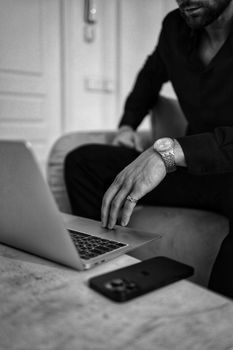 Stylish black and white photo of a man using a laptop, emphasizing elegance and professionalism.