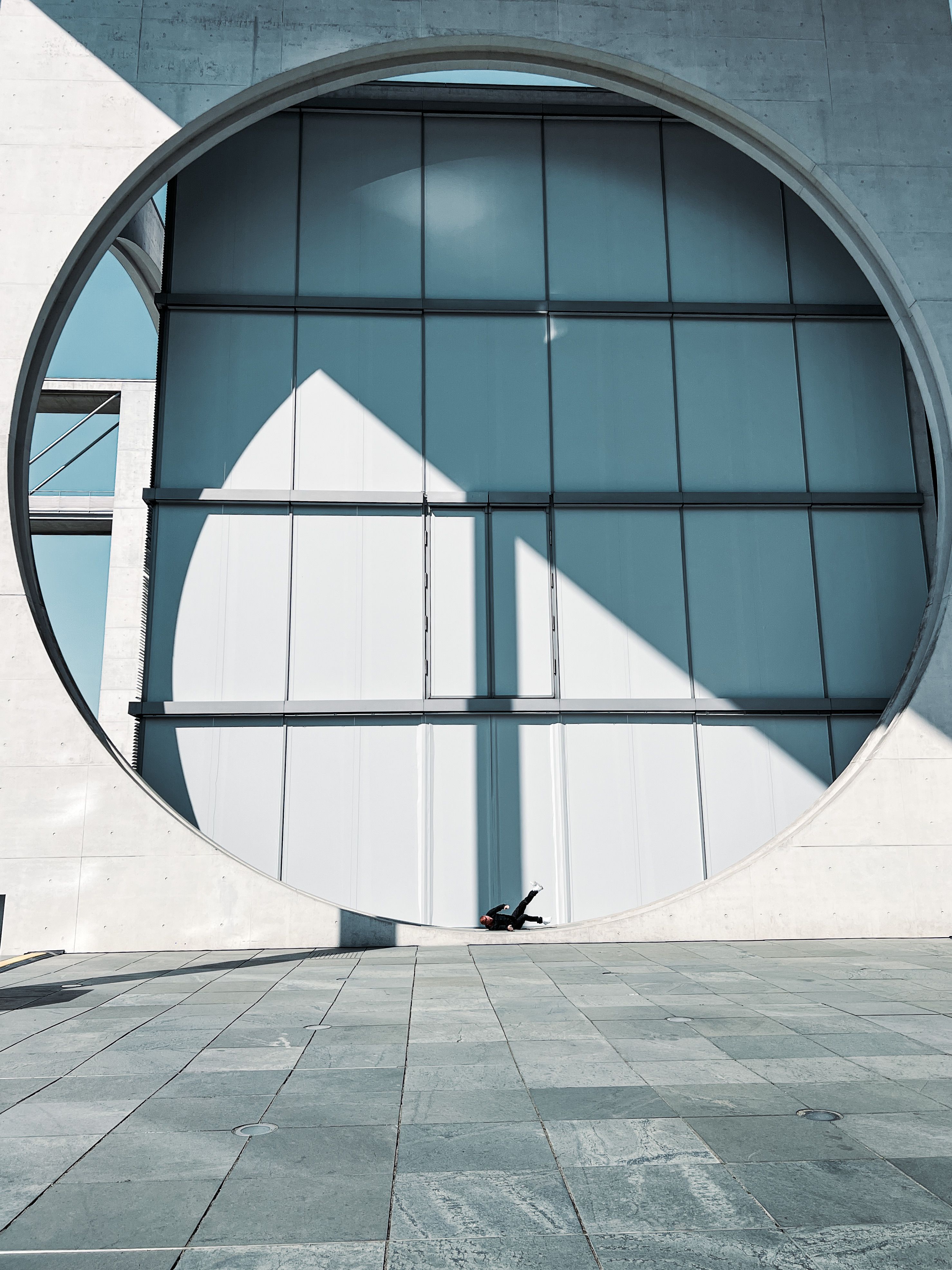Fotomural Fachada arquitectónica contemporánea con un gran diseño circular proyectando sombras en la acera.