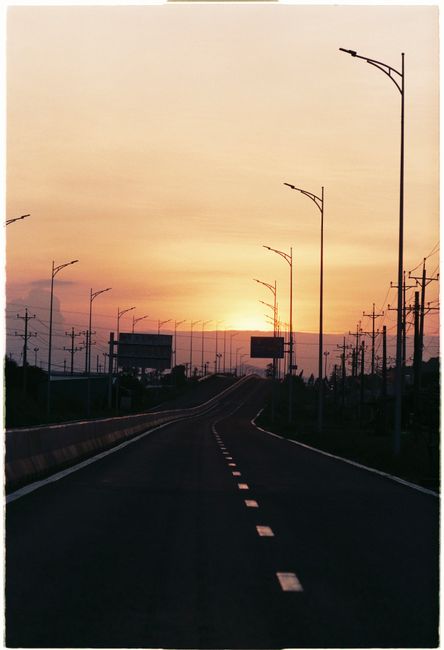 Serene road leading to horizon under pink sunset sky, empty and peaceful.