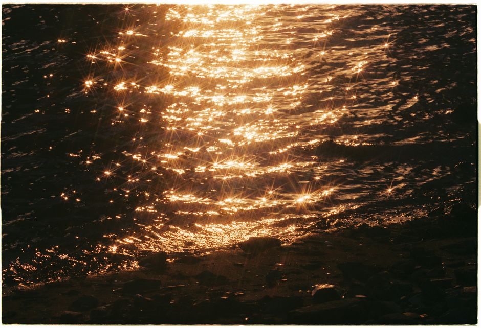 Sunset sparkle on ocean waves creating a serene golden reflection.
