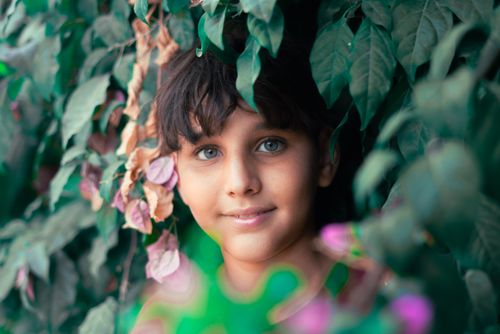 Free Captivating portrait of a child surrounded by vibrant green leaves, taken outdoors in Alger Centre, Algeria. Stock Photo