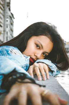 一位黑发美女在户外侧身摆姿，眼神迷人
