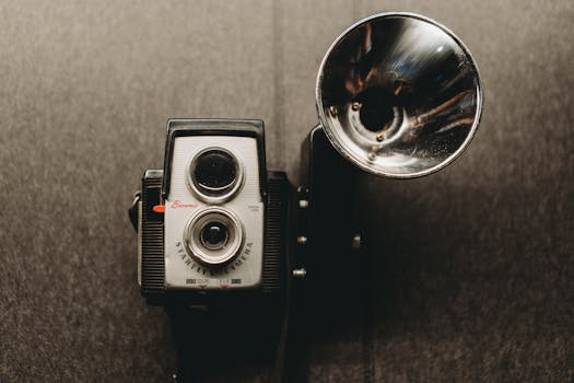 Classic Brownie Starflex camera with retro flash attachment on gray backdrop.