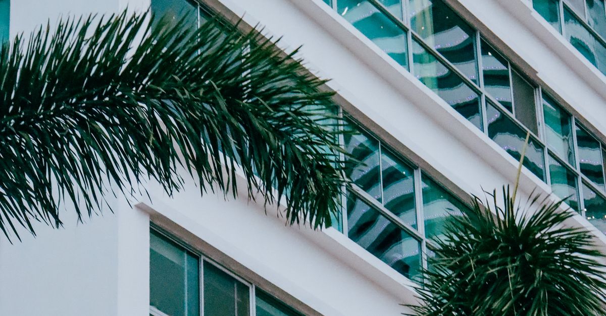 Photo by Benjamin Laina High-angle shot of a modern building with palm trees, showcasing urban architecture and tropical greenery.