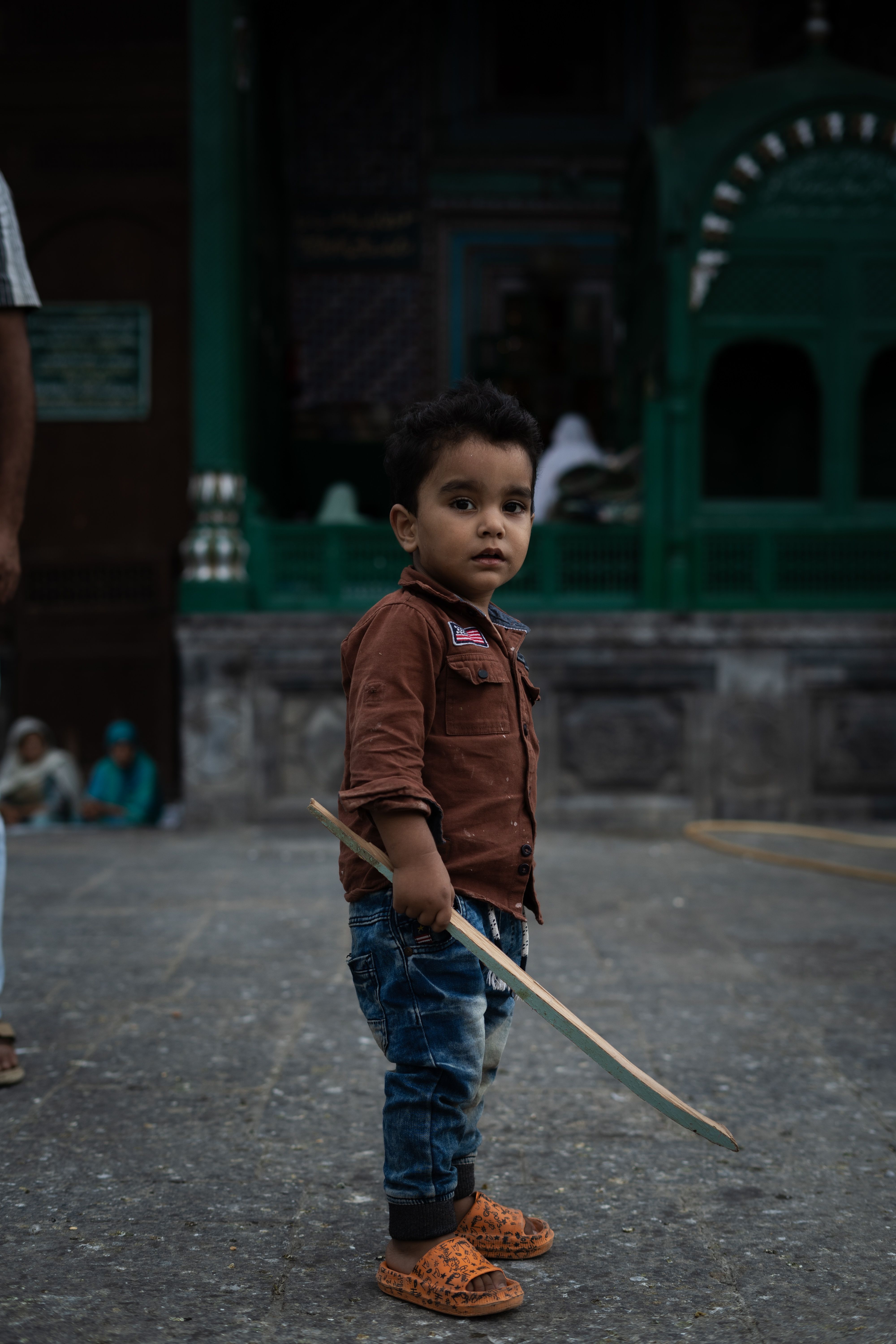 A young boy stands holding a toy sword, showcasing a curious urban moment.