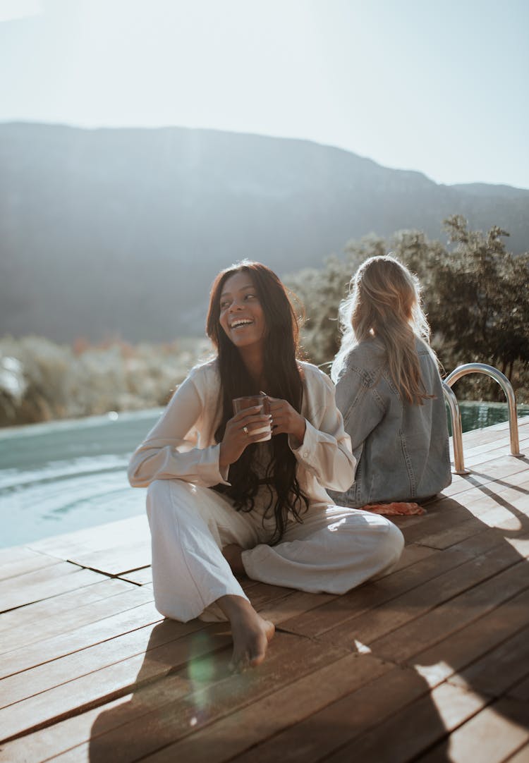 Young Women Sitting By A Pool In The Morning