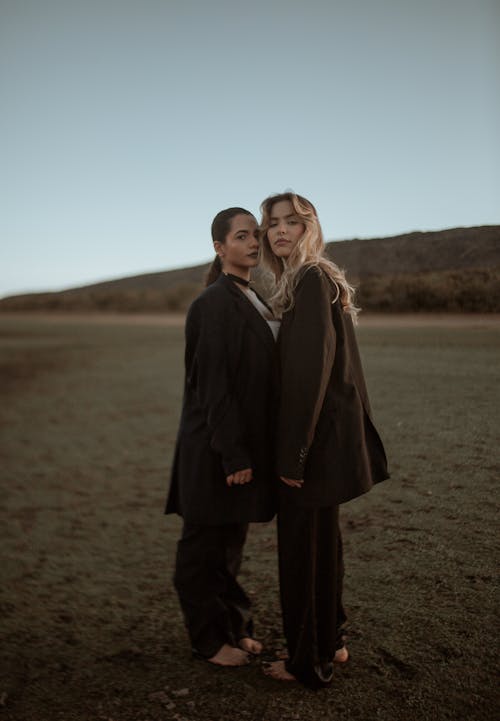Two Women in Suits Posing on a Field 