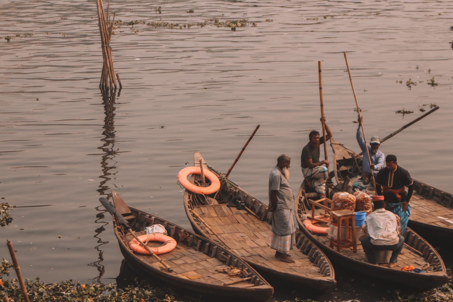 Local merchants selling goods from moored boats at a rural riverside market.