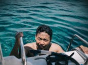 晴朗的热带水域中，成年雄性游泳后爬上了梯子，天空晴朗