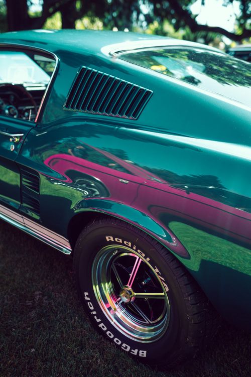 Free Close-up of a vintage Ford Mustang reflecting vibrant colors at a sunny car show. Stock Photo