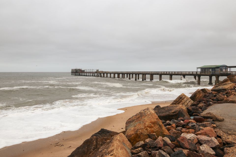 Vista pacifica della spiaggia e del molo di Swakopmund in Namibia, con onde che si infrangono sulla riva.
