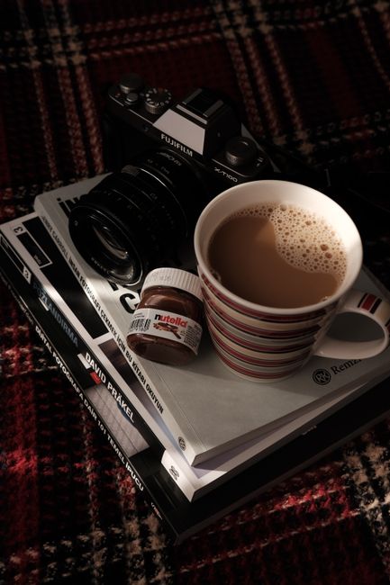 A warm, cozy setting featuring a coffee cup, a vintage camera, and books. Ideal for creative inspiration.