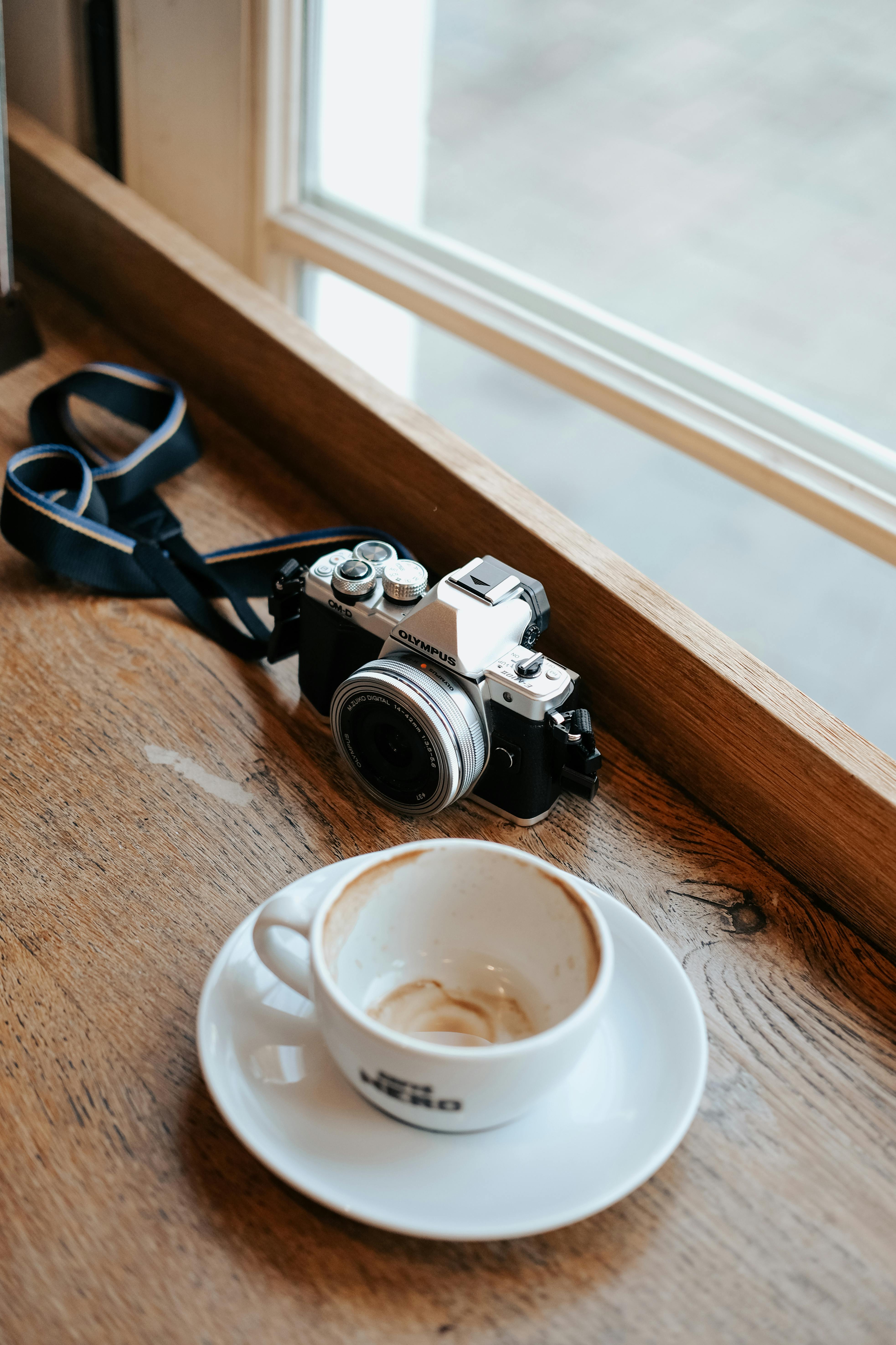 An Empty Coffee Cup and a Camera on the Table in a Cafe · Free Stock Photo