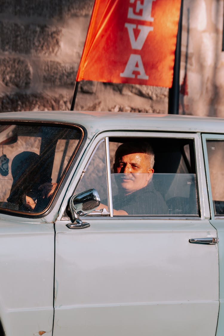 Senior Man Sitting In A White Vintage FIAT Car