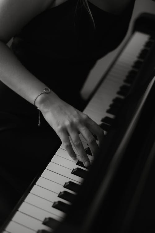 Black and White Photo of a Woman Playing a Piano
