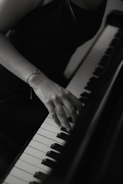 Free A woman's hand elegantly plays piano keys in a monochrome artistic shot. Stock Photo