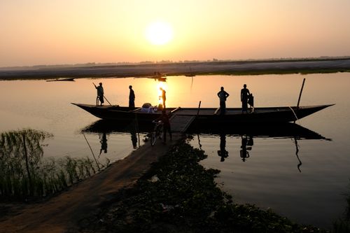 Free Silhouetted people on a boat at sunrise on a tranquil river. Stock Photo