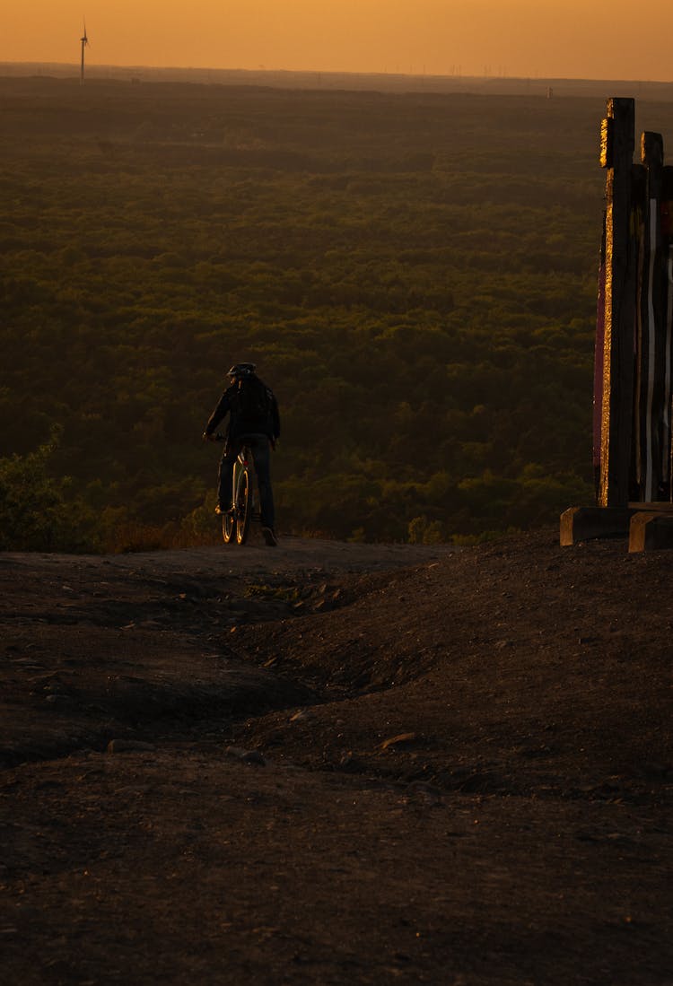 Person On Bike On Dirt Road At Sunset