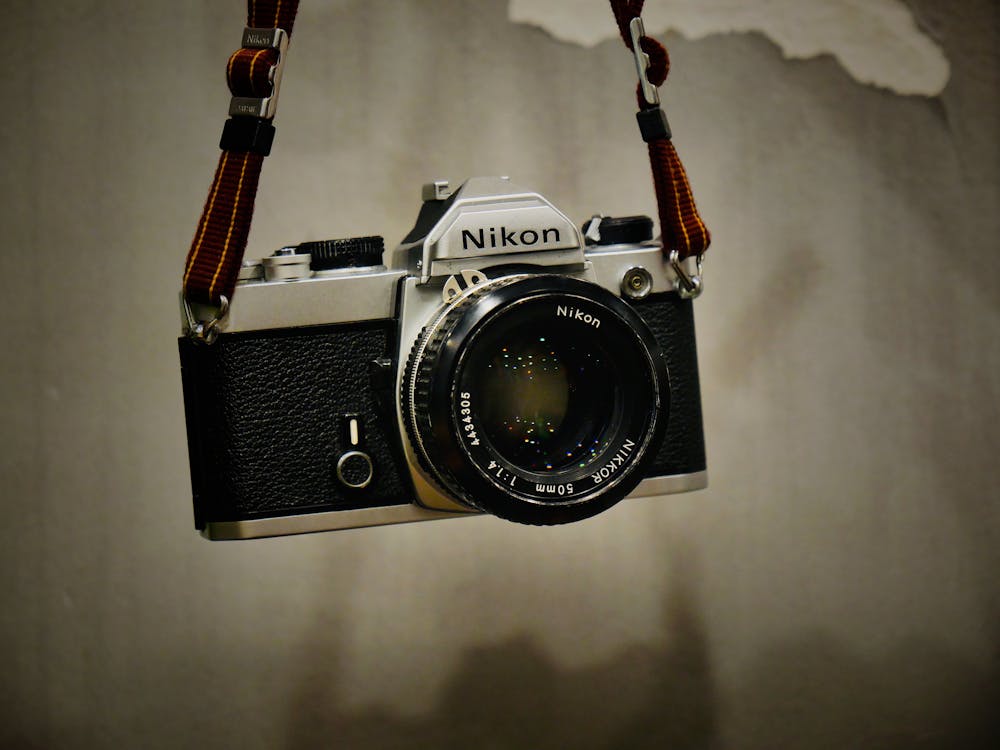 Nikon Camera Hanging on Gray Background · Free Stock Photo