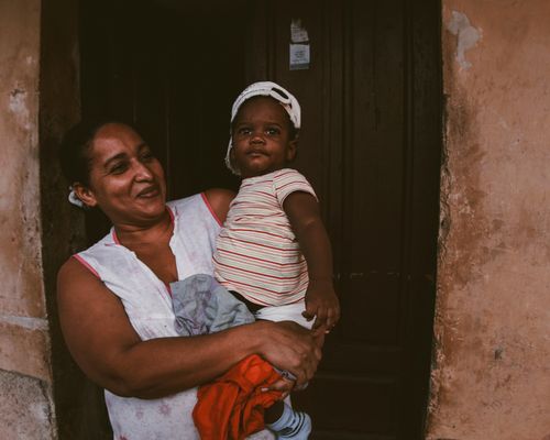 Free A joyful woman holds a smiling child at a rustic doorway. Stock Photo