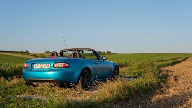 A blue convertible in the scenic countryside of Słomniki, Poland on a sunny day.