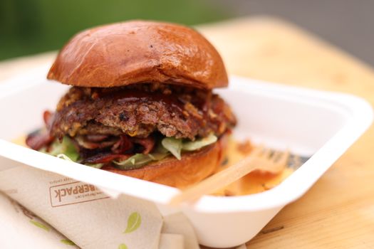 Close-up of a gourmet beef burger in eco-friendly packaging, perfect for food lovers.