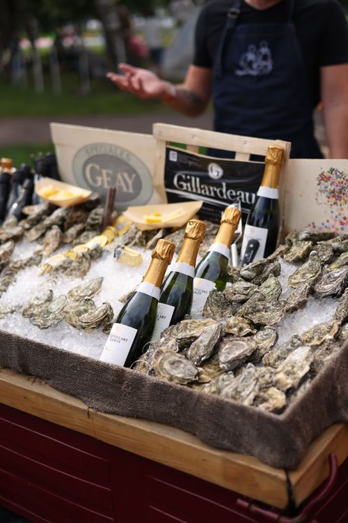Free Elegantly displayed bottles of champagne with fresh oysters on ice at an outdoor stall. Stock Photo