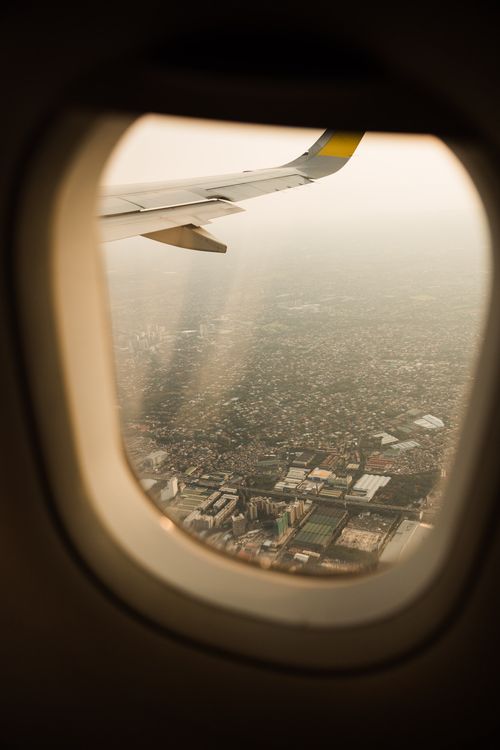 Free View of a cityscape through an airplane window with aircraft wing visible. Stock Photo