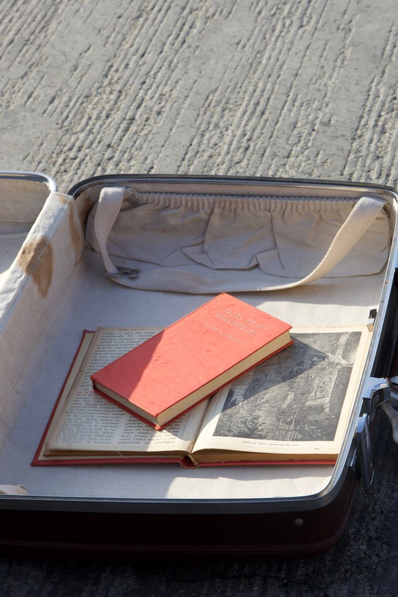 An open vintage suitcase contains old books on a concrete surface, capturing a nostalgic travel theme. An open vintage suitcase contains old books on a concrete surface, capturing a nostalgic travel theme.