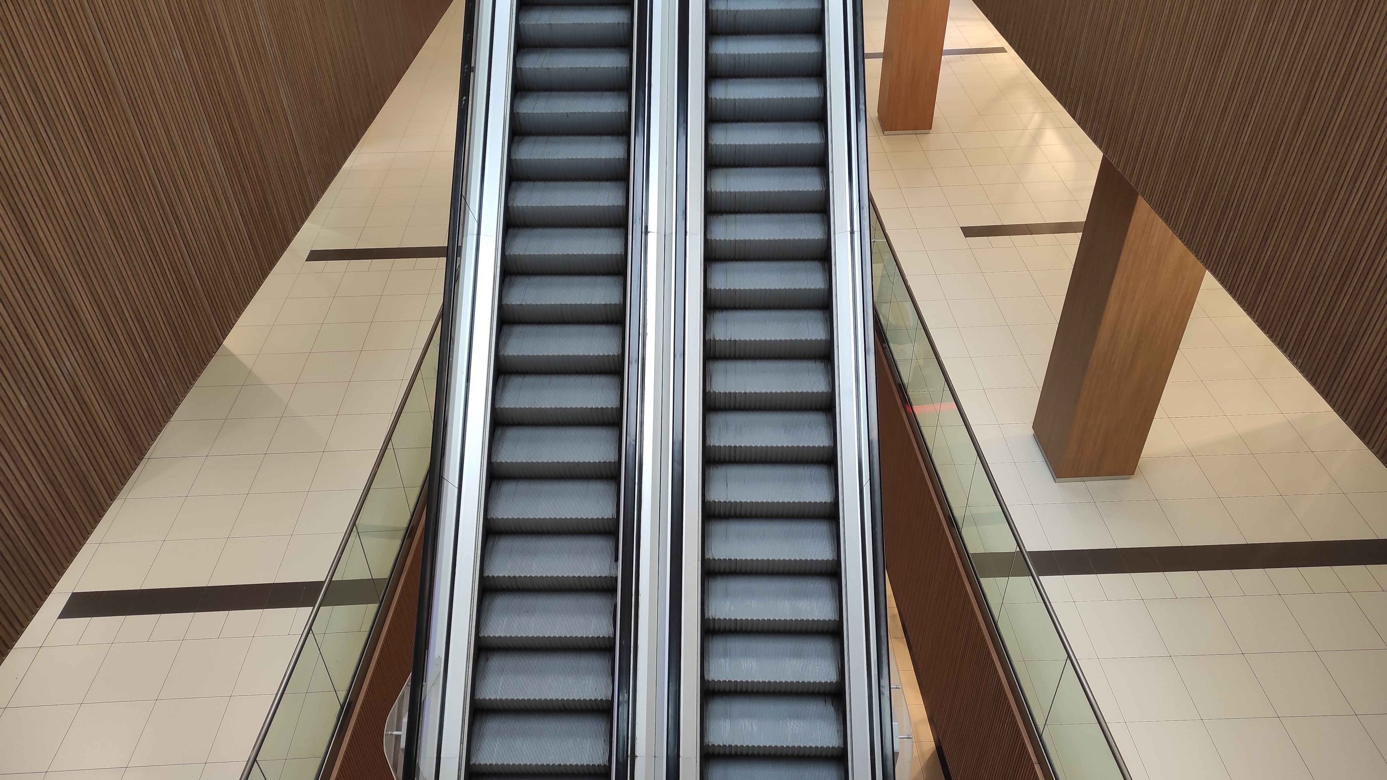 View of an empty shopping mall interior highlighting a central escalator.