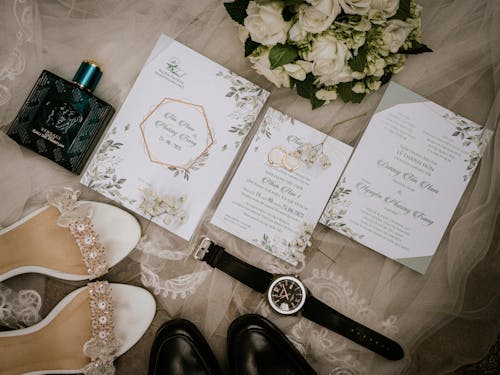 Top View of Wedding Rings Lying on Cards among Items Worn by Bride and Groom 