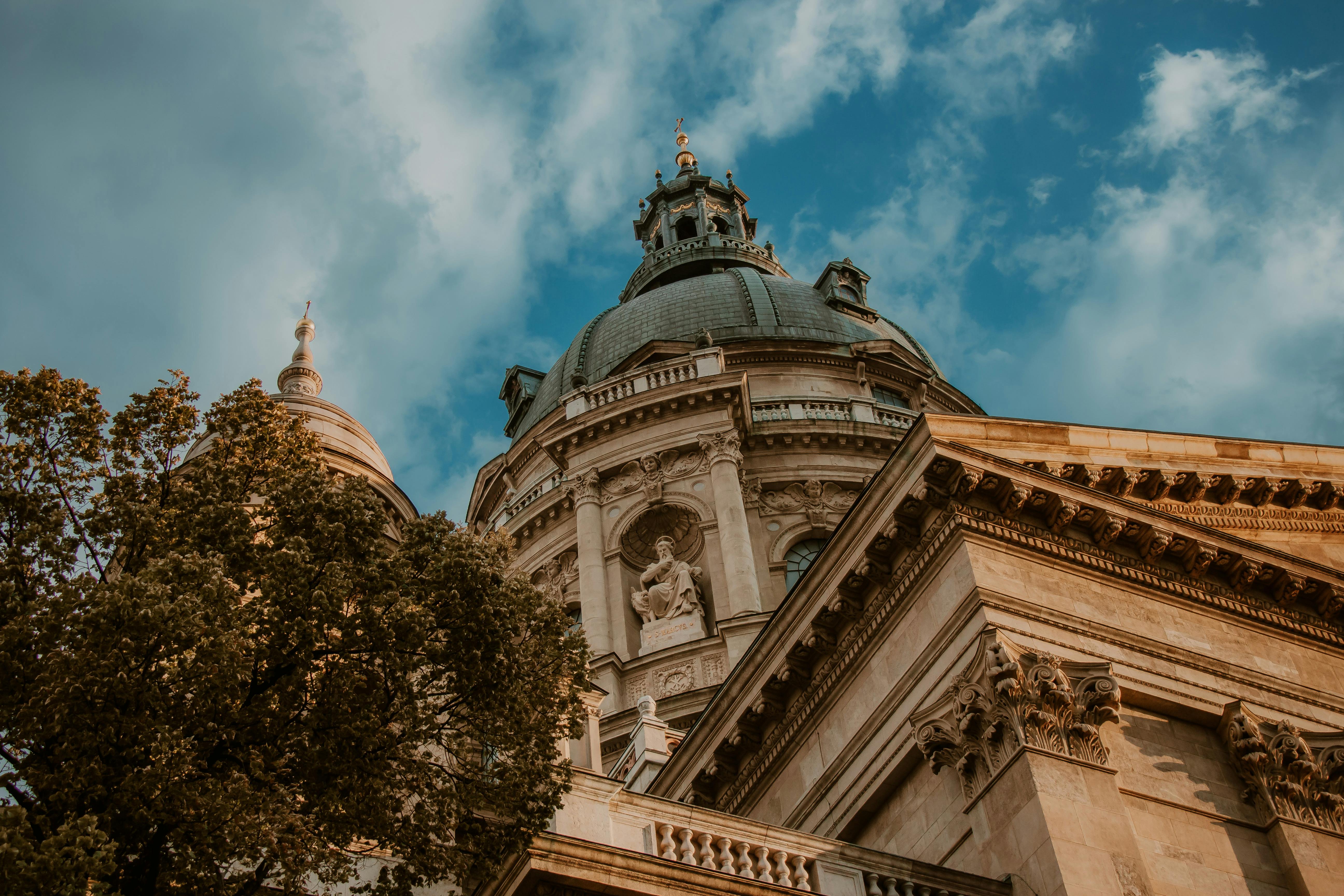 Low angle view of St. Stephen's Basilica in Budapest, showcasing baroque architecture against a bright sky.