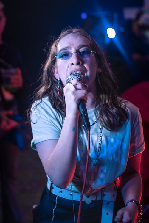 Young Woman Holding a Microphone and Singing at a Concert 