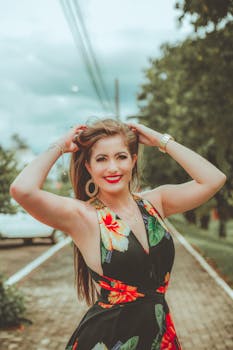 一位快乐的女子留着棕色长发，穿着充满活力的花卉连衣裙在户外摆姿势