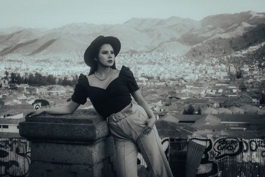 Stylish woman in black attire with cityscape backdrop exuding elegance.