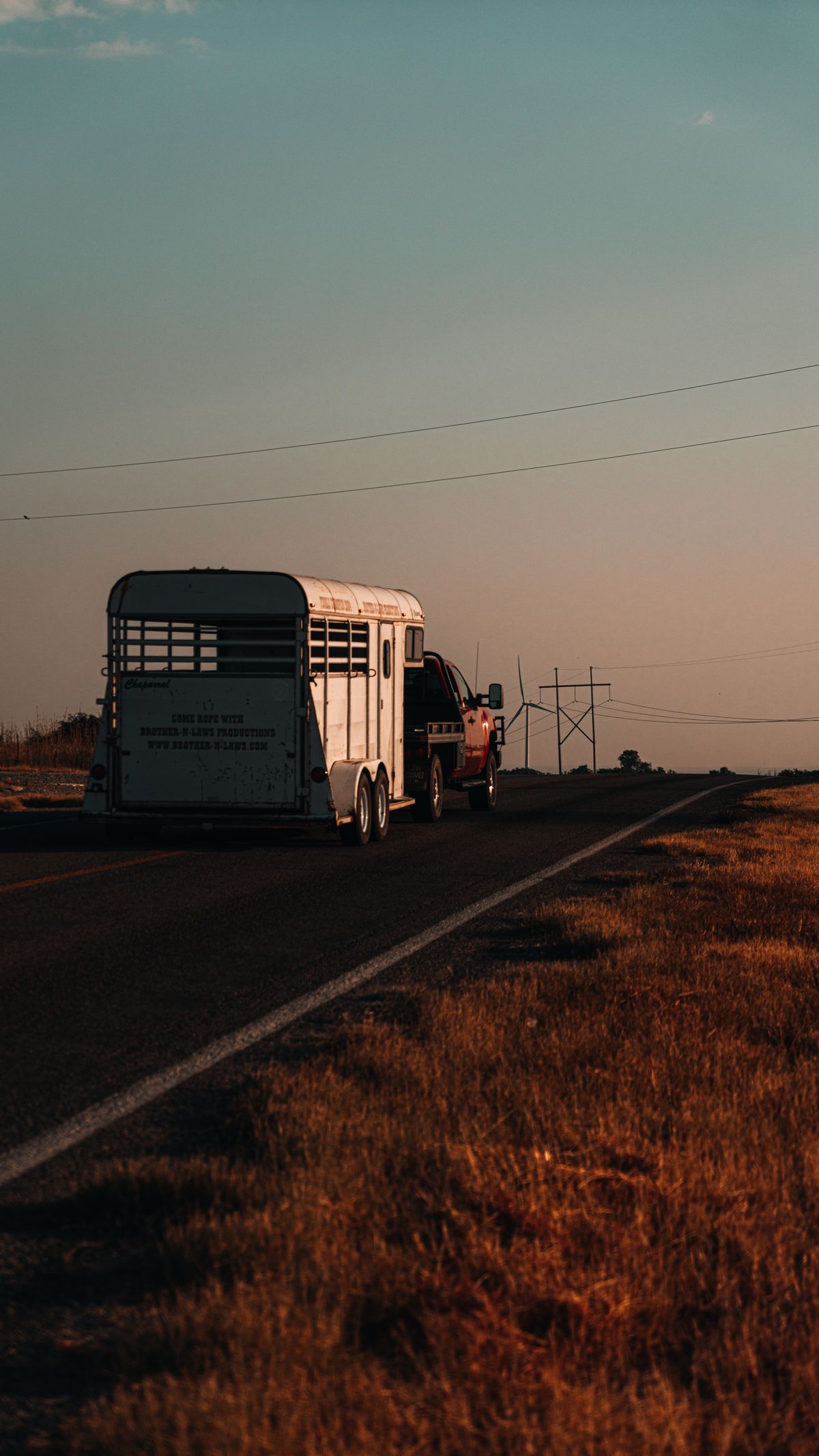 Truck towing a trailer down a rural road during sunset demonstrating safe trailer hauling