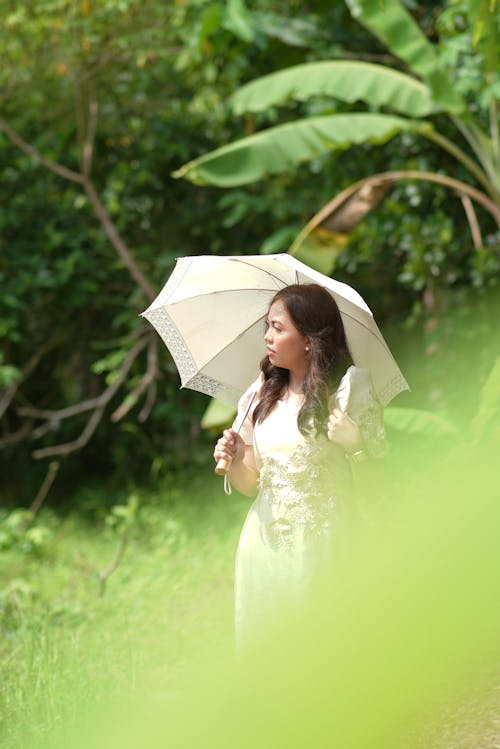 A Woman Standing in the Garden with a Sun Umbrella 