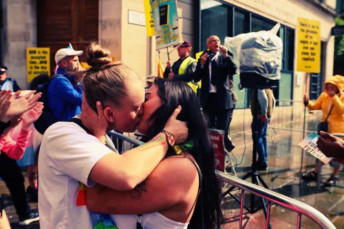 Free A couple shares a kiss during a vibrant street parade in Manchester, England. Stock Photo