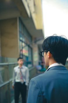 Back view of a man in a blazer and glasses in an urban setting, focusing on city life and fashion.