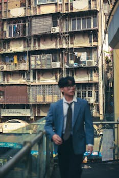 A man in a blue jacket walking past urban residential buildings, showcasing city life.