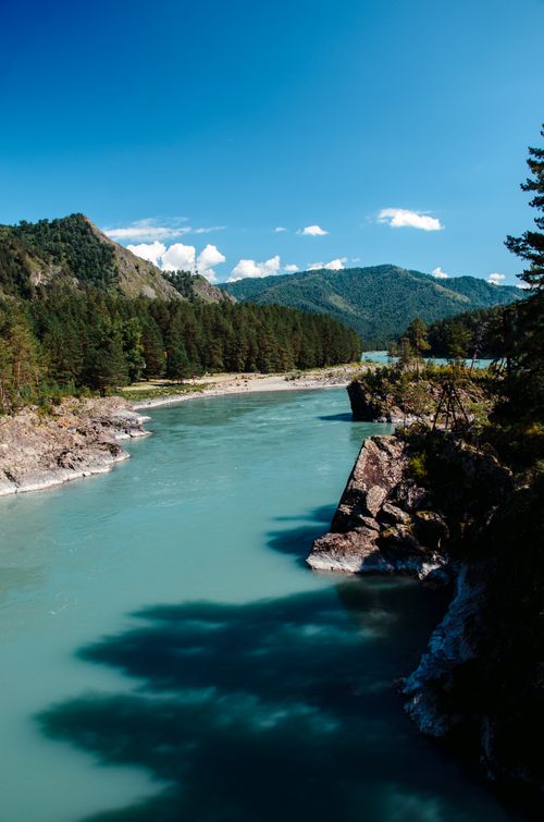 Free Beautiful clear river flowing through a mountain landscape under a blue sky. Stock Photo