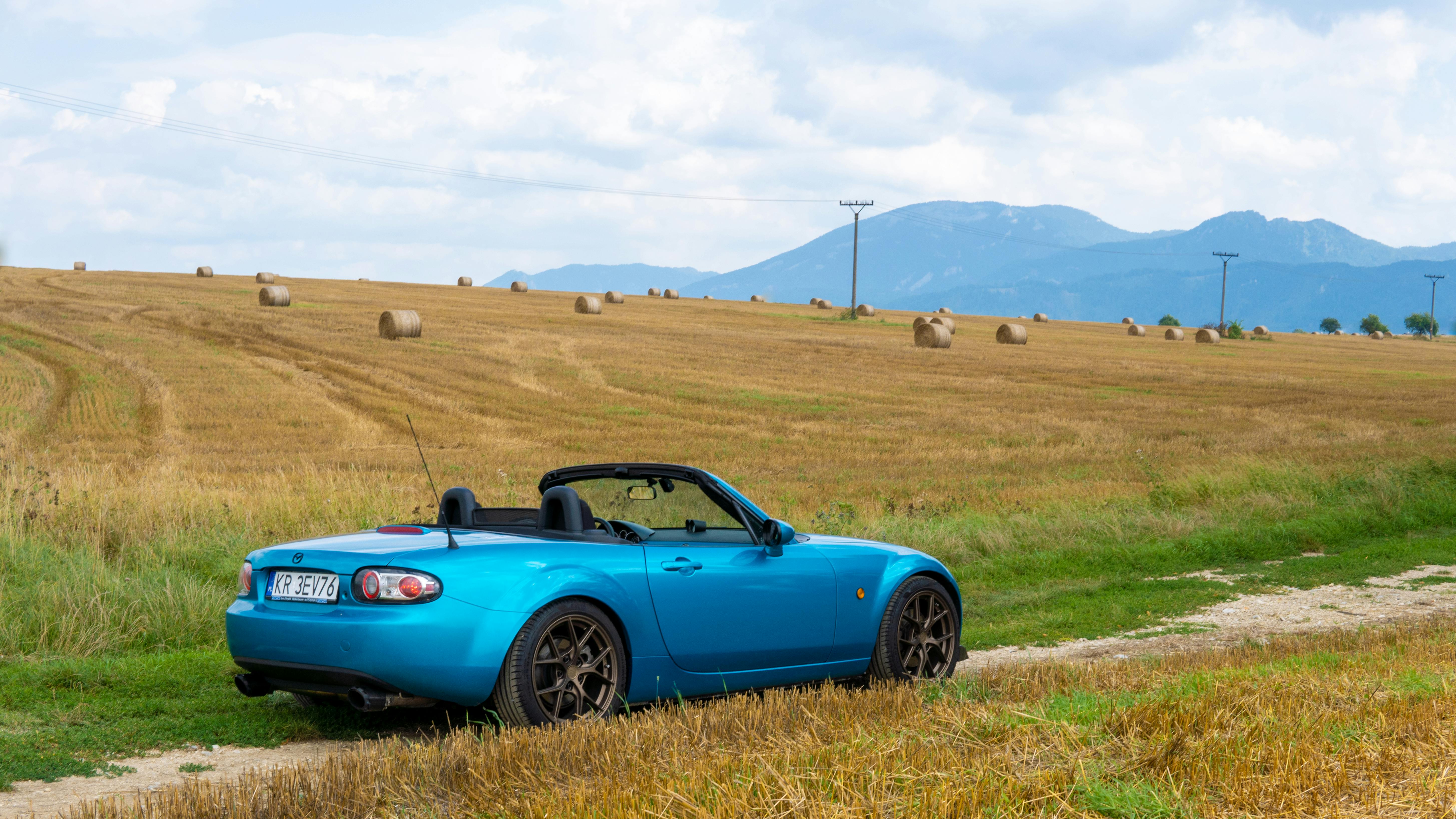 A blue convertible sports car on a rural dirt road in Turčianske Teplice, Slovakia.